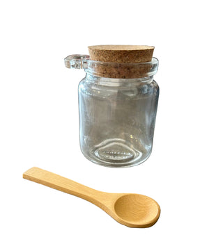 Clear glass jar with cork lid and wooden spoon on a concrete surface